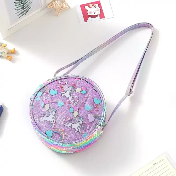 Rund lila barnväska med hjärtan, regnbågar och glittereffekt. Lätt modell med dragkedja och justerbar rem för bekväm användning.